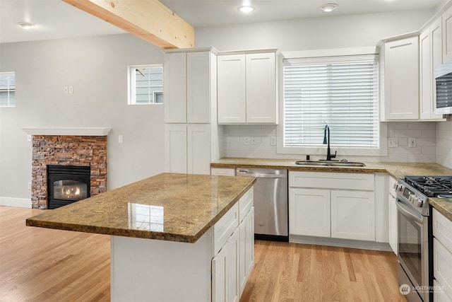 kitchen featuring sink, stainless steel appliances, backsplash, and a fireplace