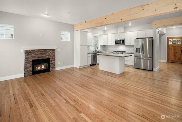 kitchen featuring stainless steel appliances, a center island, decorative backsplash, white cabinets, and light hardwood / wood-style flooring