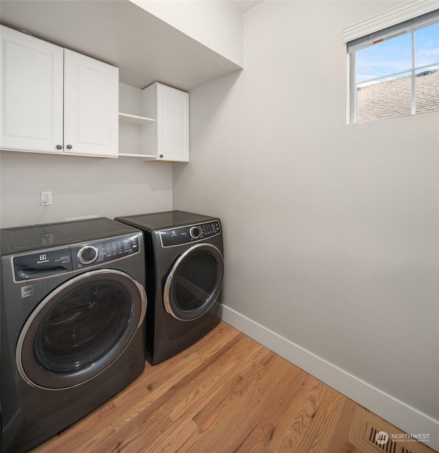 laundry room with washer and dryer, cabinets, and light hardwood / wood-style flooring