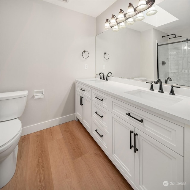 bathroom with toilet, wood-type flooring, a skylight, vanity, and an enclosed shower