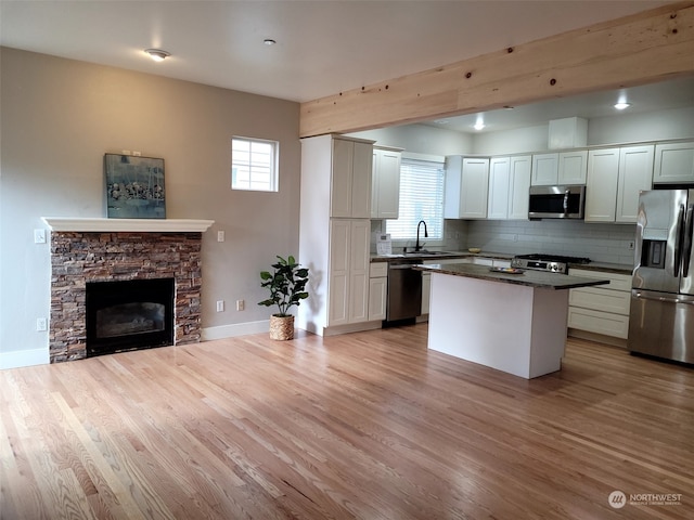 kitchen with appliances with stainless steel finishes, a center island, decorative backsplash, sink, and white cabinetry