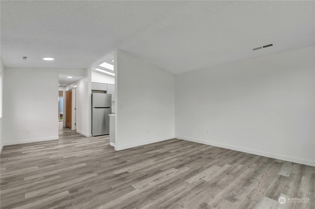 unfurnished living room with light wood-type flooring and vaulted ceiling