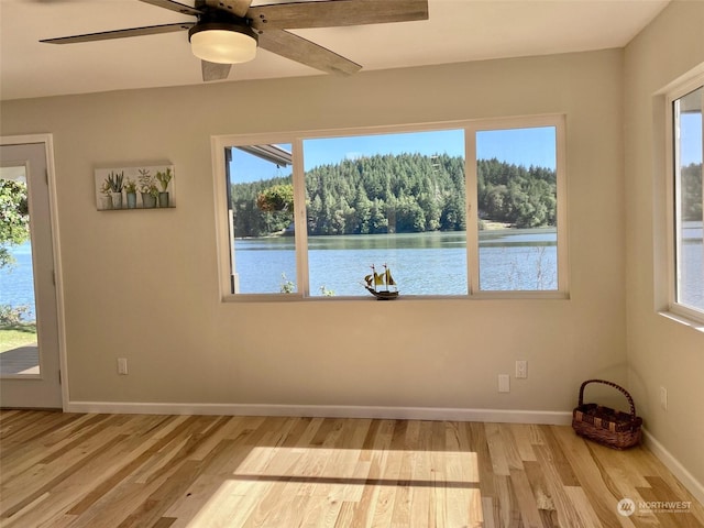 empty room with a water view, light hardwood / wood-style flooring, and ceiling fan