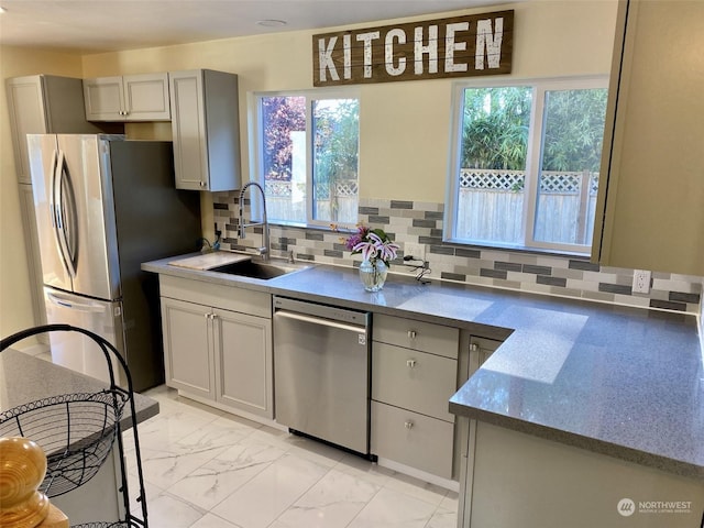 kitchen with gray cabinetry, decorative backsplash, sink, and stainless steel appliances