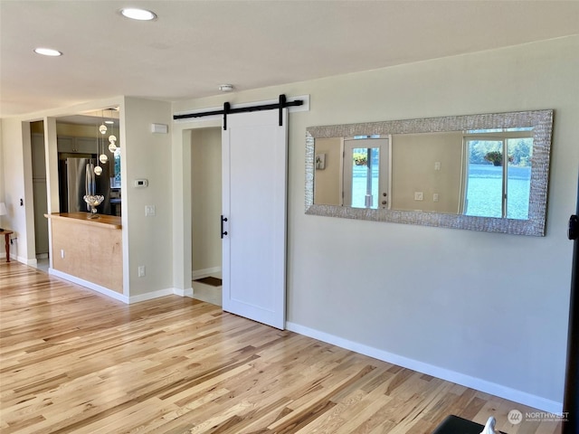 empty room featuring a barn door and light hardwood / wood-style flooring