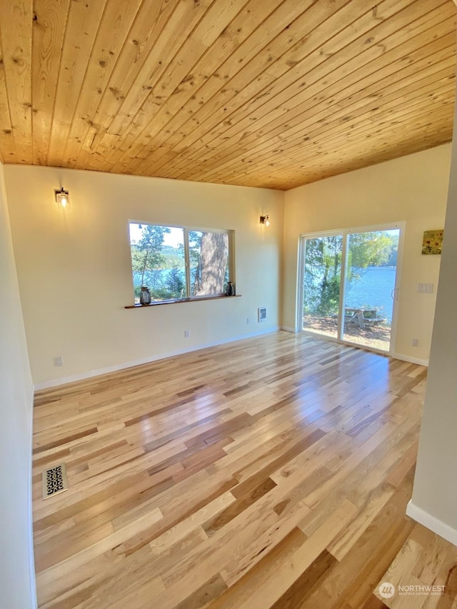 unfurnished living room featuring a wealth of natural light, light wood-type flooring, and wood ceiling