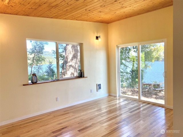 spare room with plenty of natural light, a water view, wood ceiling, and light hardwood / wood-style flooring