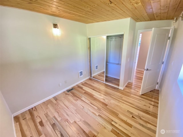 unfurnished bedroom with wooden ceiling, light wood-type flooring, and a closet