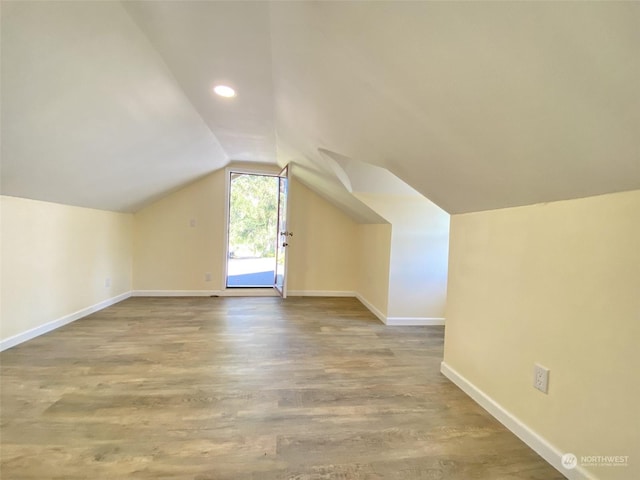 additional living space featuring wood-type flooring and vaulted ceiling