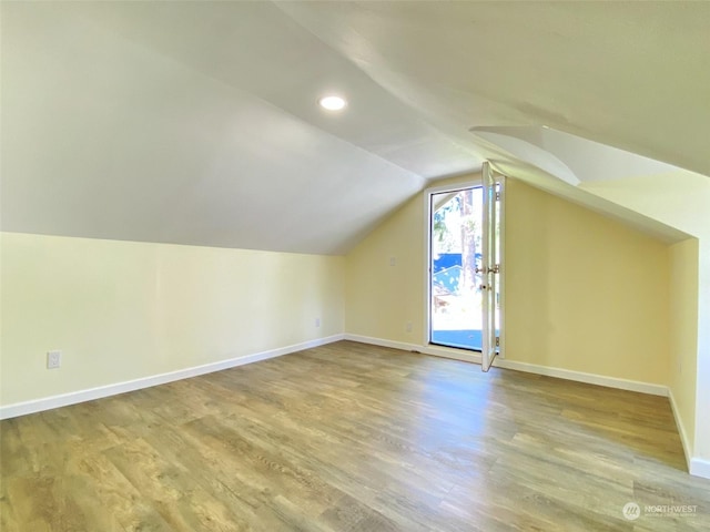 additional living space with hardwood / wood-style floors and lofted ceiling