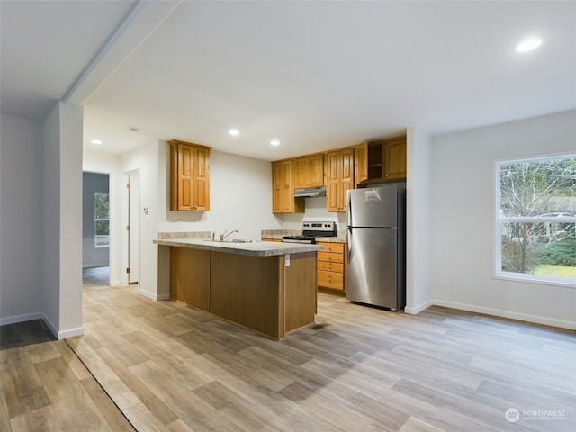 kitchen with kitchen peninsula, appliances with stainless steel finishes, a kitchen breakfast bar, sink, and light hardwood / wood-style floors