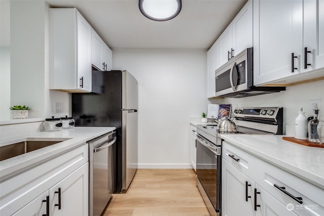 kitchen featuring light stone countertops, light hardwood / wood-style flooring, white cabinets, and stainless steel appliances