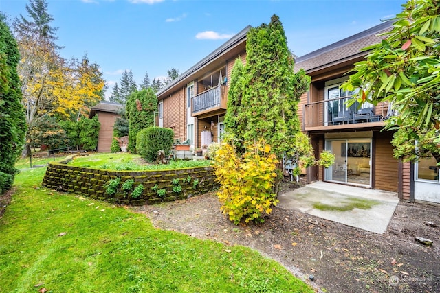 back of property with a patio area, a yard, and a balcony