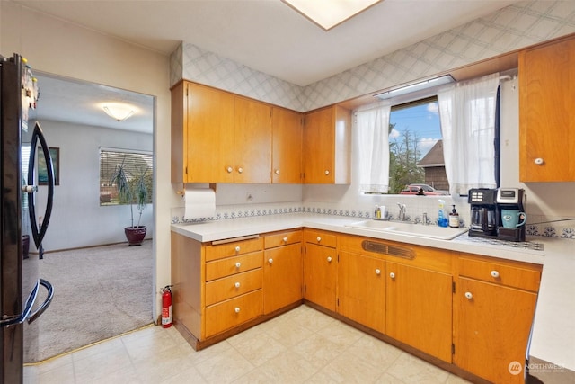 kitchen featuring stainless steel fridge, sink, and light carpet