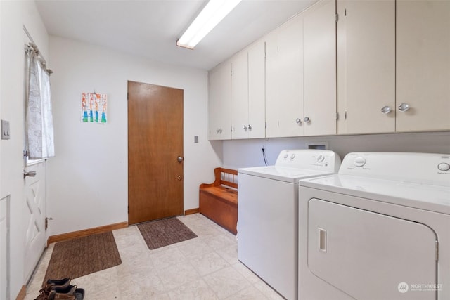 clothes washing area with separate washer and dryer and cabinets