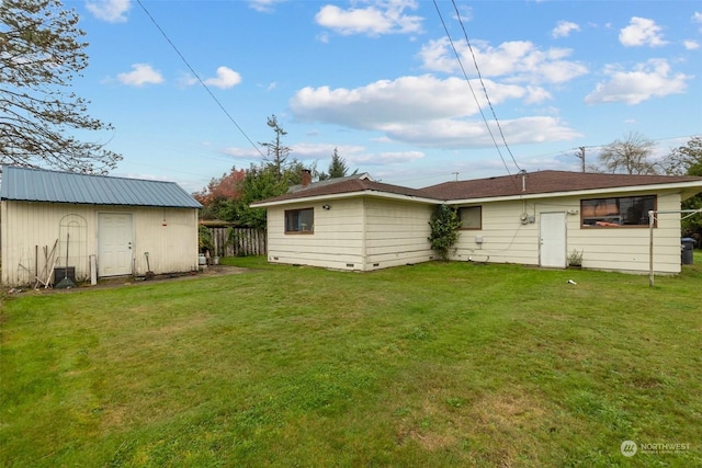 rear view of property featuring a yard and a storage unit