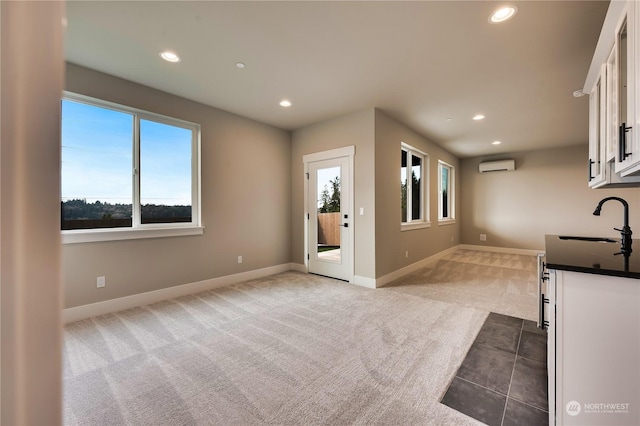 interior space with light colored carpet, an AC wall unit, sink, and white cabinets