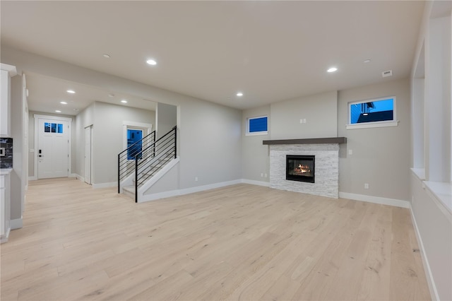 20239 125th Ave NE Unit Sm2-11, Bothell, WA 98011 - unfurnished living room featuring a stone fireplace, light wood-style flooring, recessed lighting, baseboards, and stairway