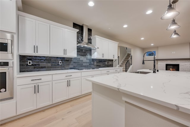 20239 125th Ave NE Unit Sm2-11, Bothell, WA 98011 - kitchen with decorative backsplash, wall chimney range hood, a sink, light wood finished floors, and appliances with stainless steel finishes