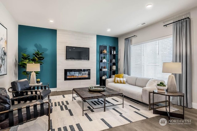 living room featuring light hardwood / wood-style floors, built in features, and a fireplace