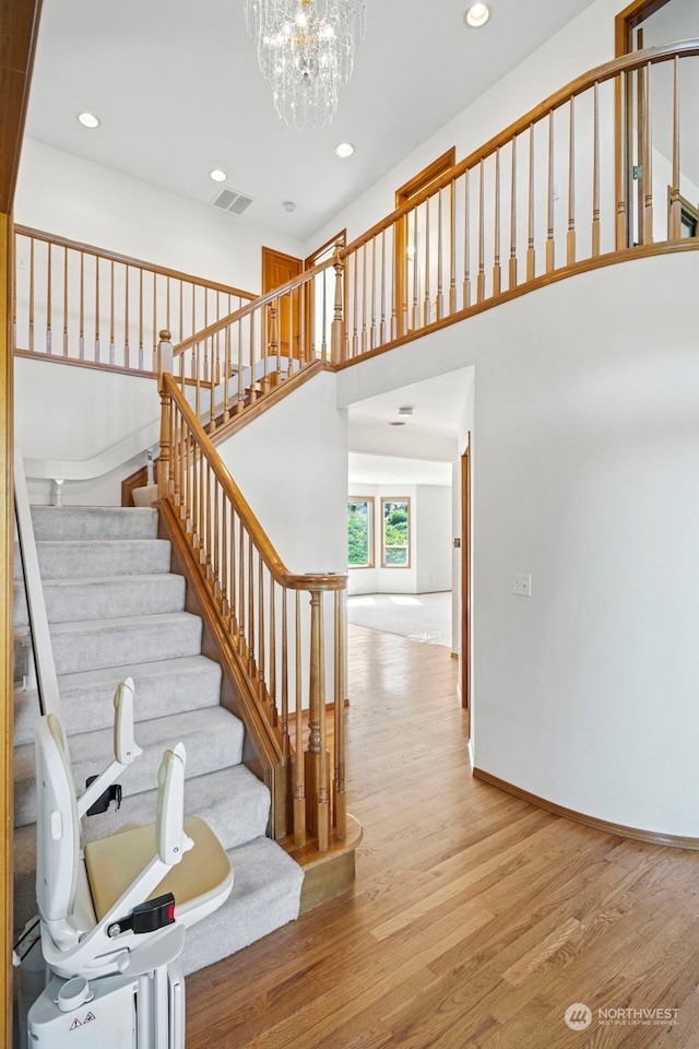 staircase featuring wood-type flooring and a notable chandelier