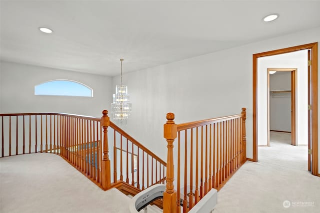 corridor featuring light colored carpet and a notable chandelier