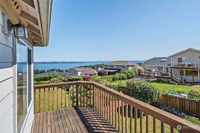 wooden terrace with a water view and a yard