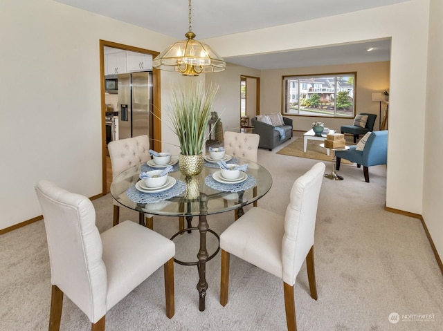 dining area with light carpet and an inviting chandelier