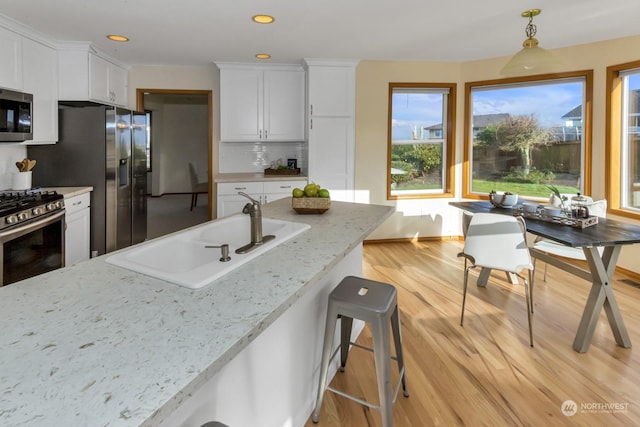 kitchen featuring decorative backsplash, sink, white cabinetry, light stone countertops, and stainless steel appliances