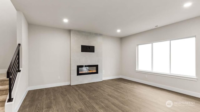 unfurnished living room with hardwood / wood-style floors and a tiled fireplace