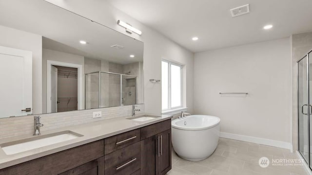 bathroom with tile patterned floors, vanity, decorative backsplash, and plus walk in shower