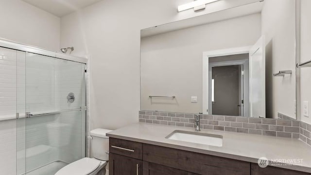 bathroom with vanity, tasteful backsplash, toilet, and a shower with door