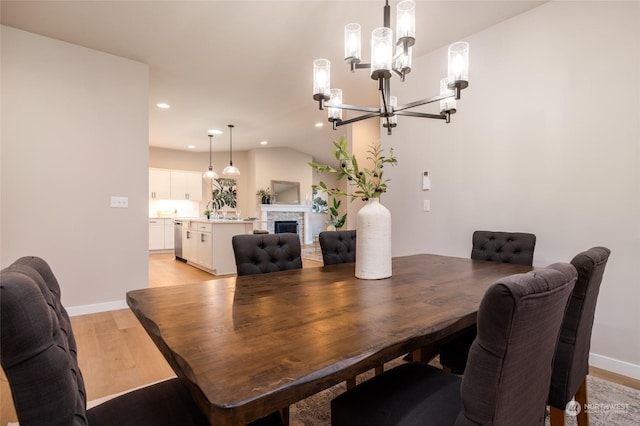 dining room featuring a fireplace, a chandelier, light hardwood / wood-style flooring, and sink