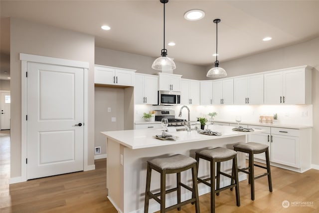 kitchen featuring white cabinets, stainless steel appliances, and a kitchen island with sink