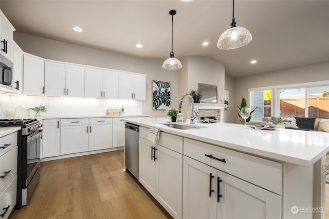 kitchen featuring decorative light fixtures, stainless steel appliances, white cabinetry, and sink