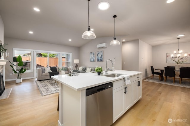 kitchen featuring sink, stainless steel dishwasher, a wall mounted AC, decorative light fixtures, and a center island with sink