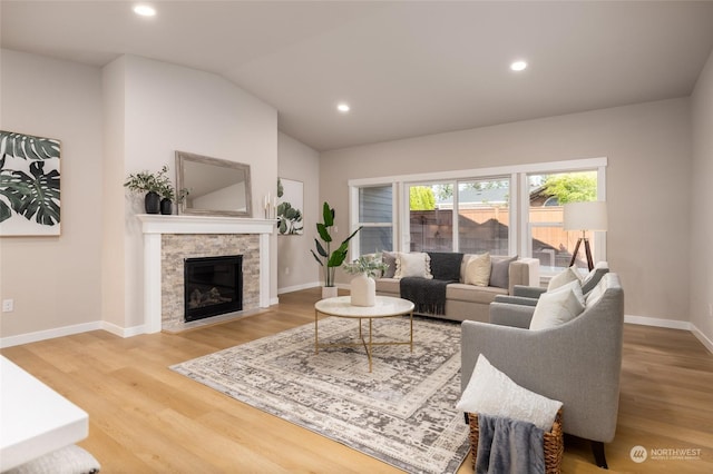 living room with a stone fireplace, hardwood / wood-style floors, and lofted ceiling