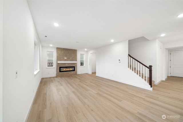 unfurnished living room with a tile fireplace and light hardwood / wood-style flooring