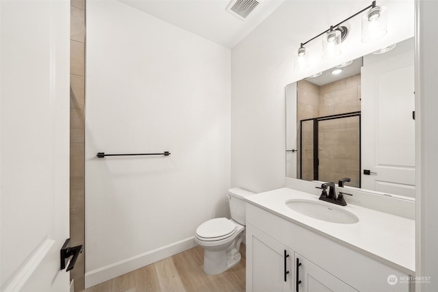 bathroom featuring vanity, wood-type flooring, an enclosed shower, and toilet