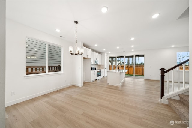 unfurnished living room featuring light hardwood / wood-style floors, sink, and an inviting chandelier