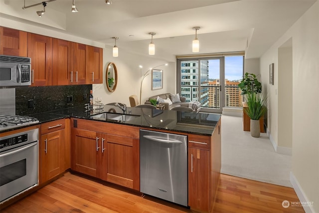 kitchen featuring stainless steel appliances, sink, decorative light fixtures, dark stone countertops, and kitchen peninsula