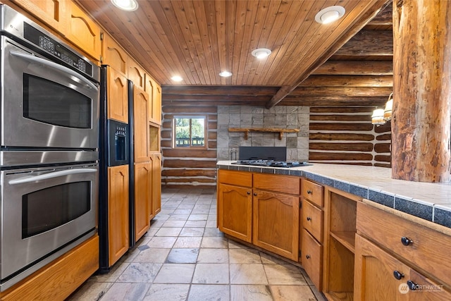 kitchen featuring tile countertops, black gas stovetop, stainless steel double oven, rustic walls, and wood ceiling