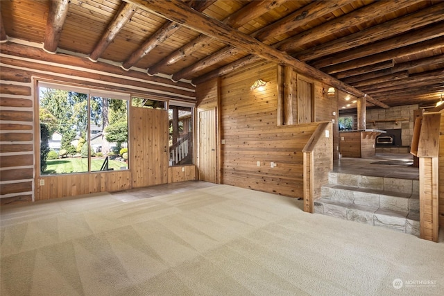 carpeted spare room featuring beamed ceiling, wooden walls, and wooden ceiling