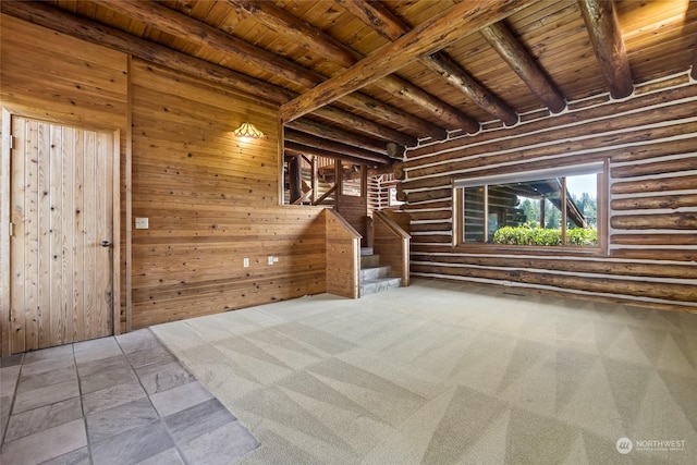 unfurnished room with wooden walls, log walls, beamed ceiling, and wood ceiling