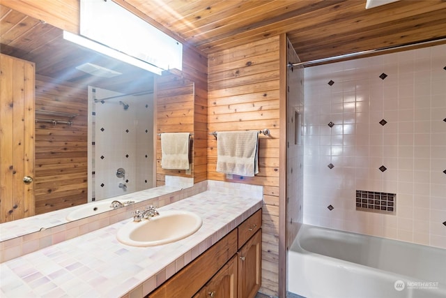 bathroom featuring tiled shower / bath combo, vanity, wood ceiling, and wooden walls