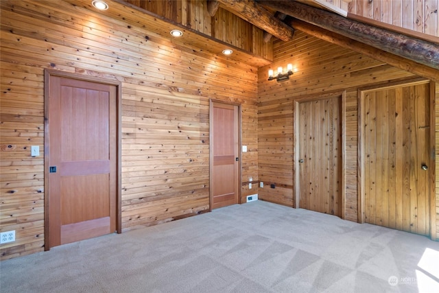 interior space with carpet, beam ceiling, and wooden walls