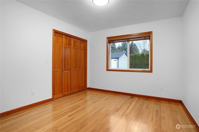 unfurnished bedroom with light hardwood / wood-style flooring and a closet