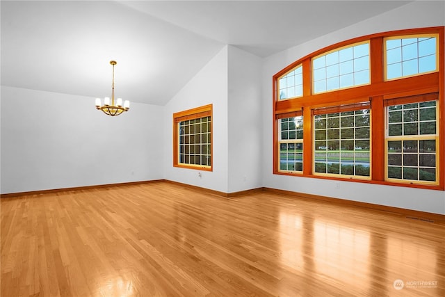 empty room with high vaulted ceiling, light hardwood / wood-style floors, and an inviting chandelier