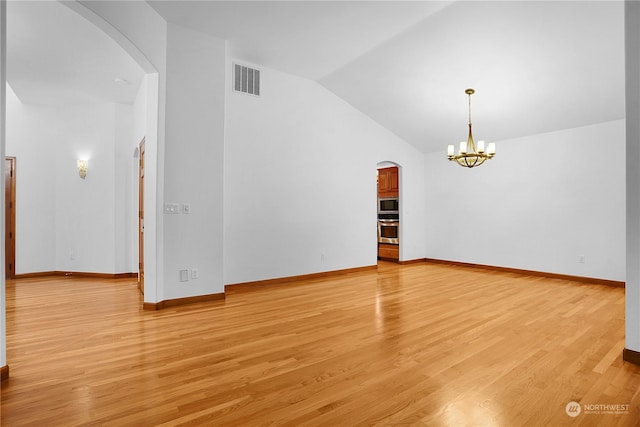 spare room with an inviting chandelier, vaulted ceiling, and light wood-type flooring