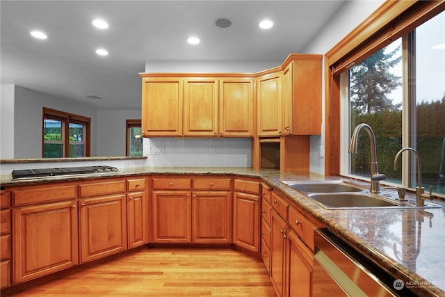 kitchen featuring backsplash, sink, light stone countertops, appliances with stainless steel finishes, and light hardwood / wood-style floors